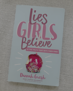 Cover of Lies Girls Believe by Dannah Gresh, featuring the title in pink lettering and a bitten candy apple on a light blue background.